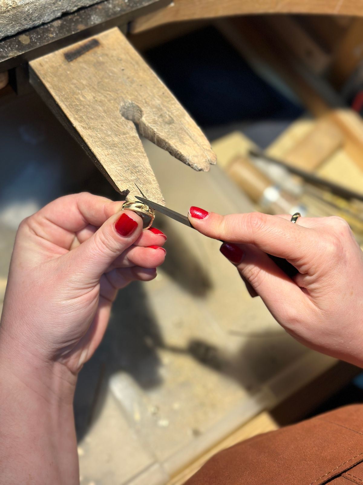Twee handen vijlen een gouden ring aan de werkbank