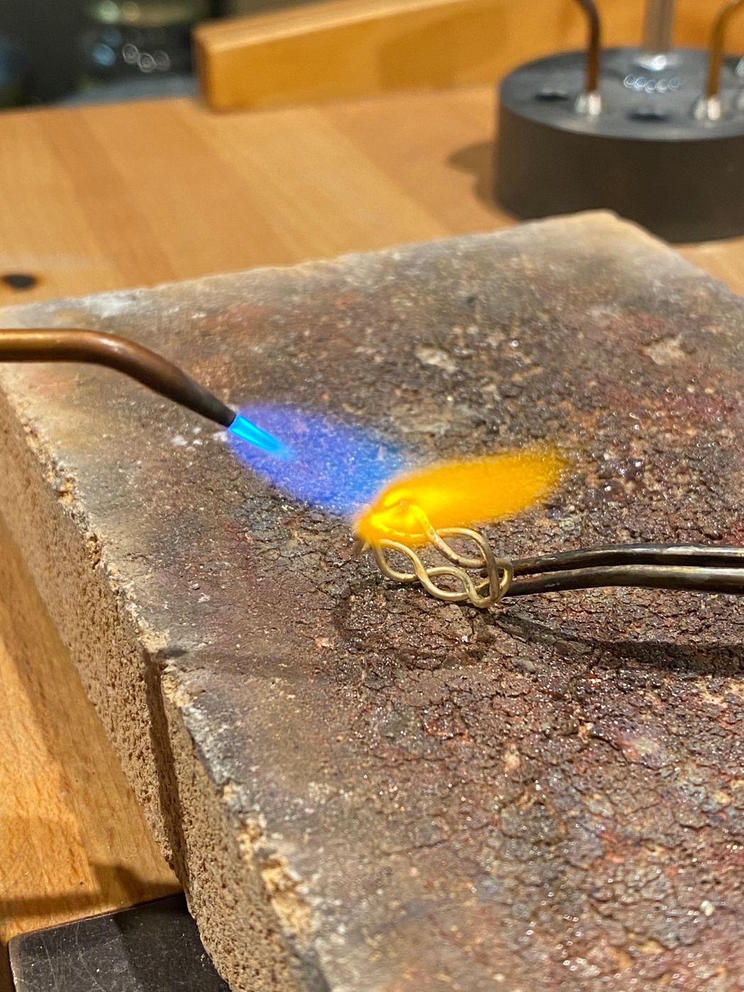 Een gouden ring wordt gesoldeerd met een vlam op een soldeersteen